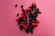 Colorful assortment of berries with a Calmerceuticals liquid collagen stick on a pink background.